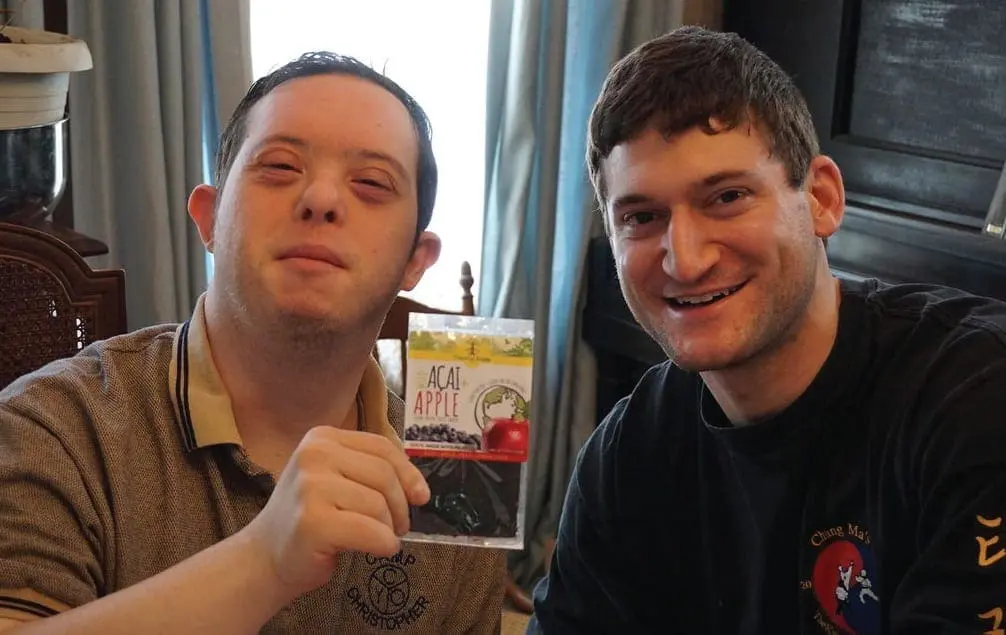 Evan Delahanty and another man smile while holding a fruit strip package.
