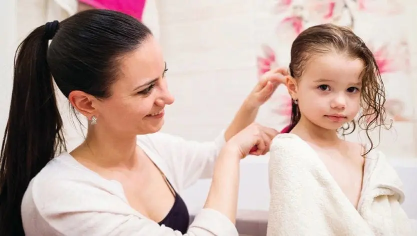 Mother combs daughter's wet hair after bath.