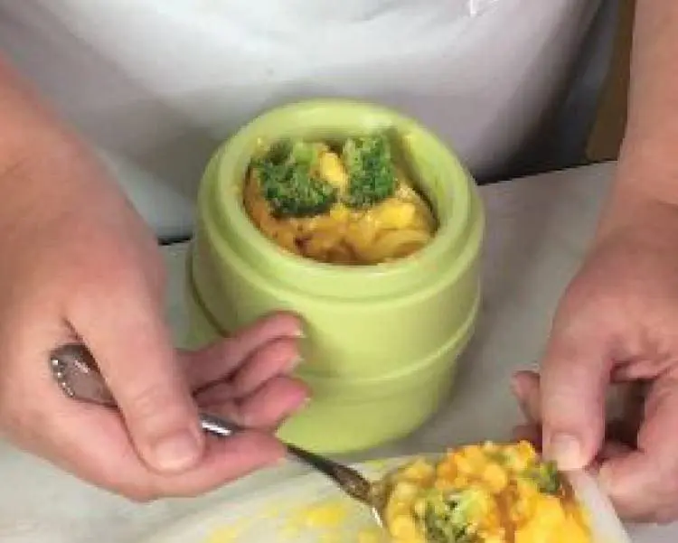 Macaroni and broccoli in a green bowl with a fork holding a spoonful.