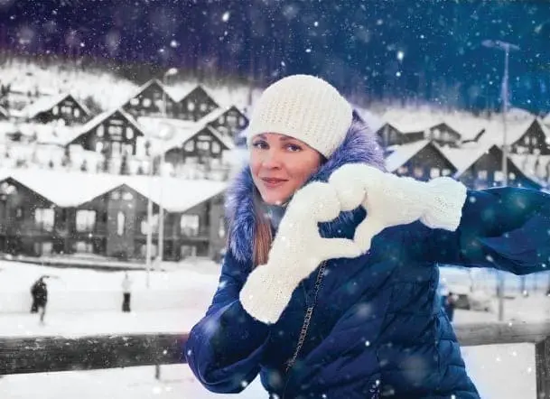 Woman in winter clothing making a heart shape with her hands