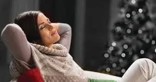 Woman resting with eyes closed in front of a Christmas tree