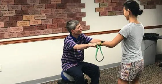 Man and woman perform a resistance band exercise.