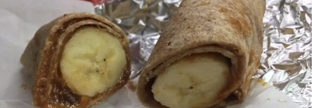 Two halves of a tortilla wrap filled with banana and peanut butter.