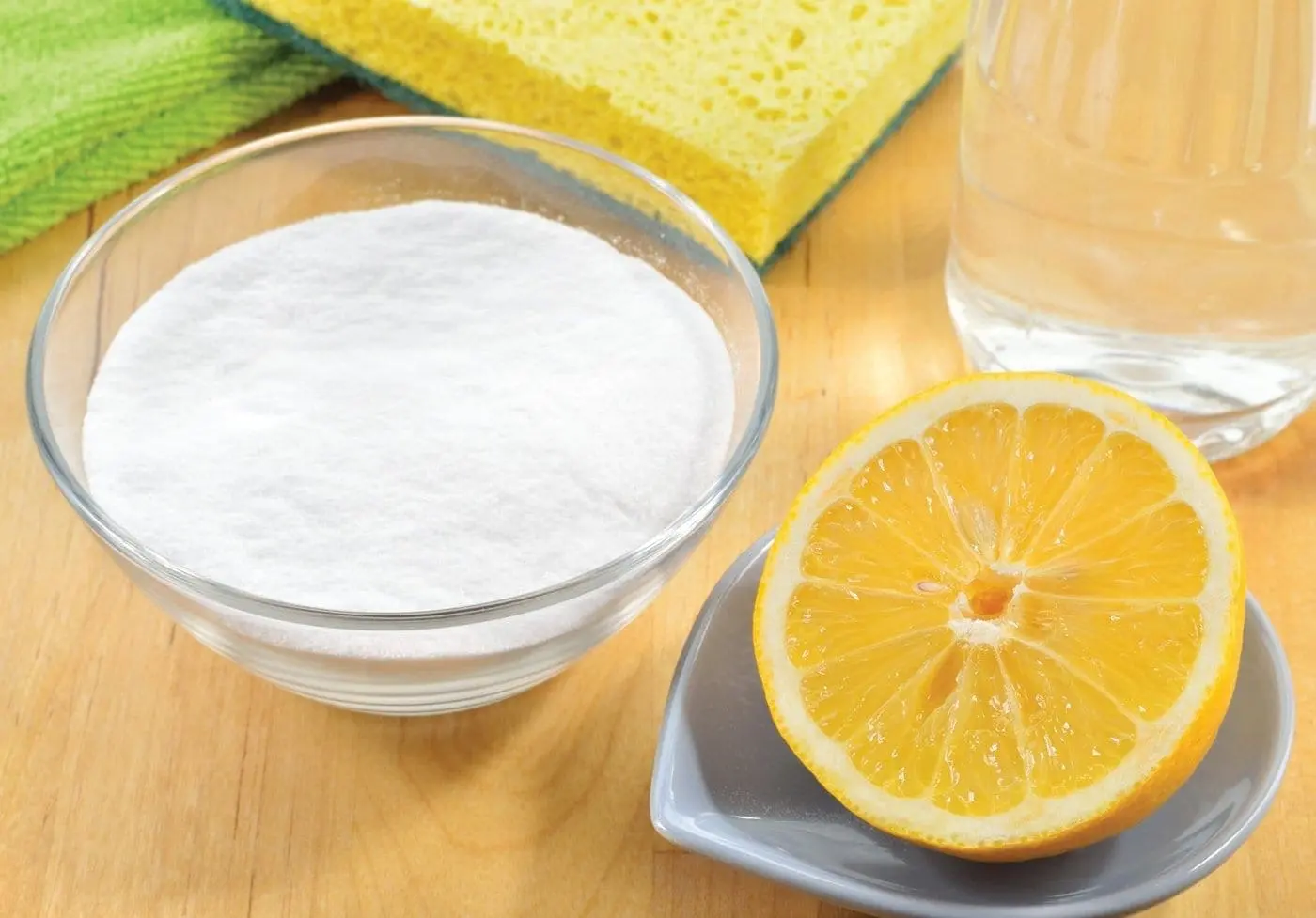 Bowl of baking soda, lemon half, sponge, and glass of water