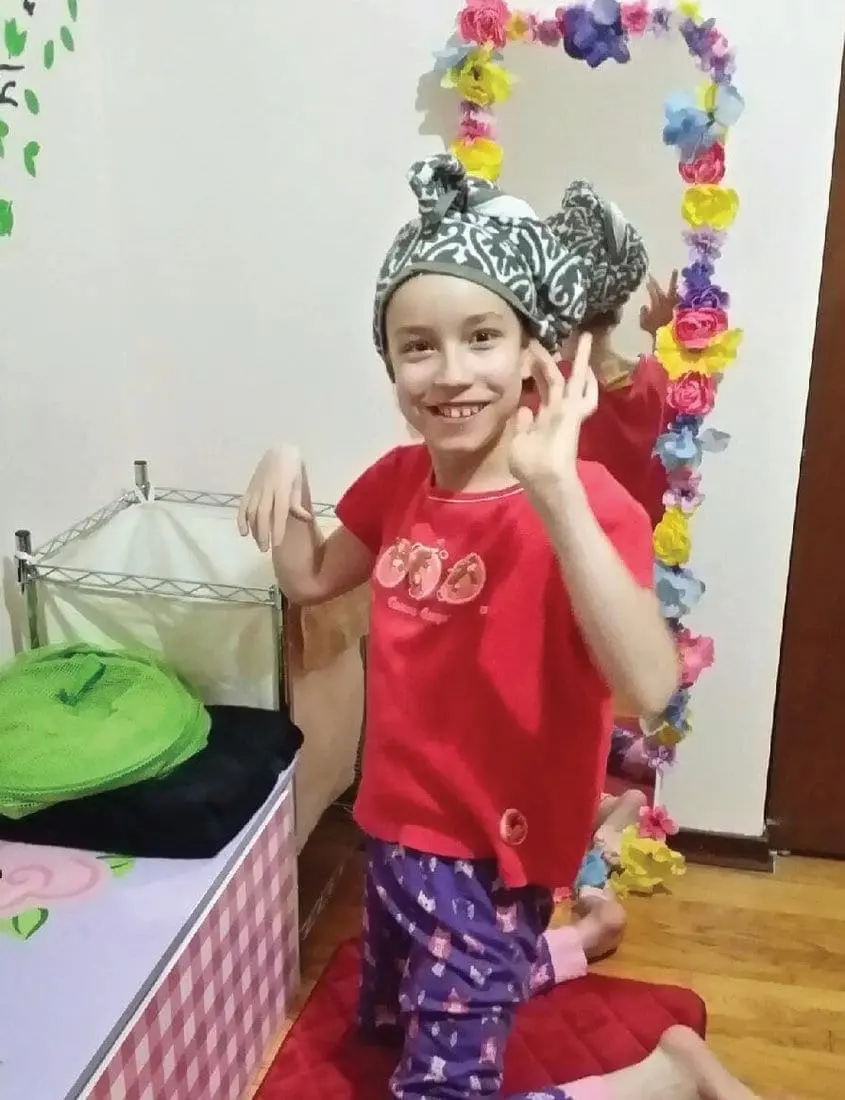 A young person smiles and poses in a colorful costume.