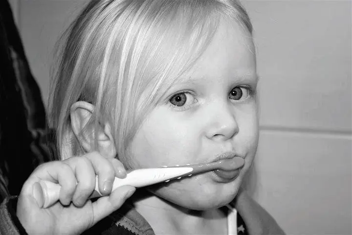 Young child brushing their teeth with a toothbrush.