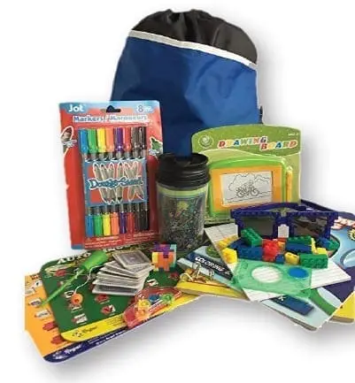 A blue drawstring bag sits behind a collection of children's toys and games including markers, a jar, and building blocks.