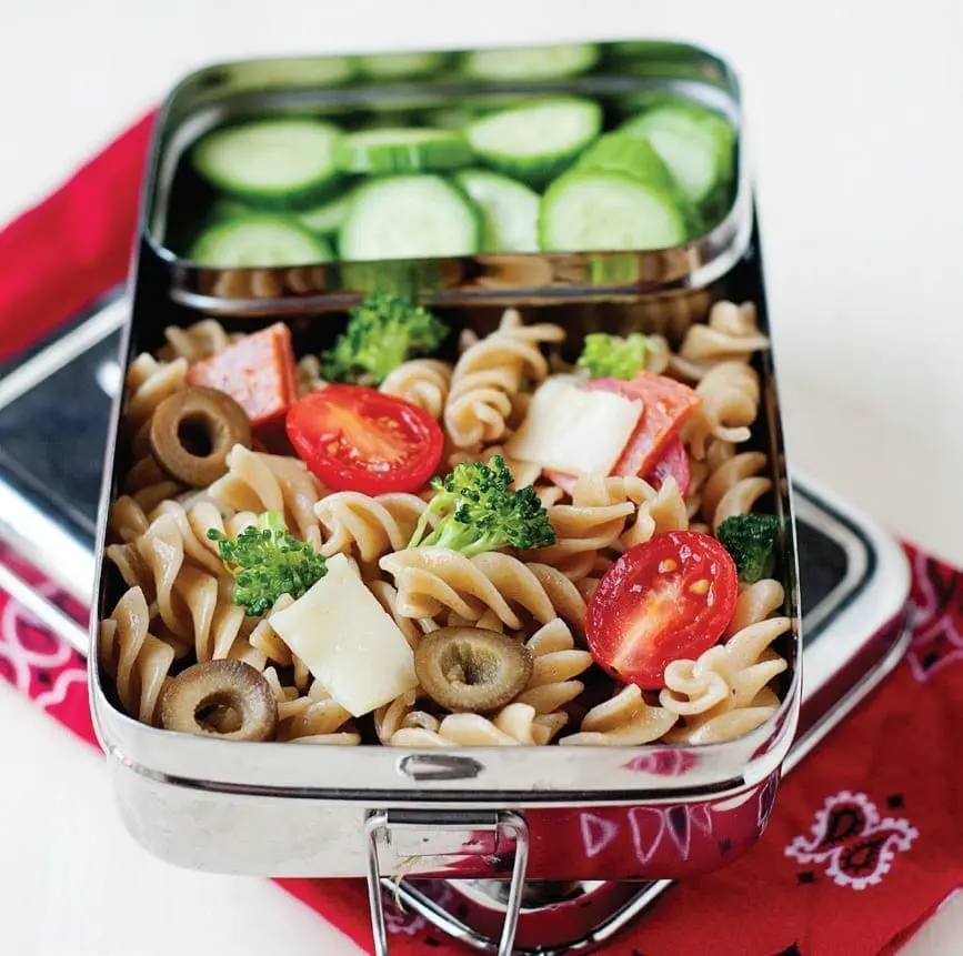 Stainless steel lunchbox filled with pasta salad and sliced cucumbers