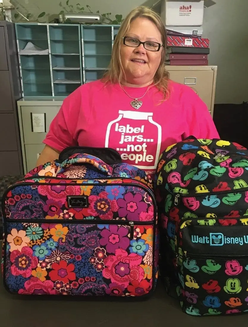 Woman in a pink t-shirt with colorful bags in front of filing cabinets