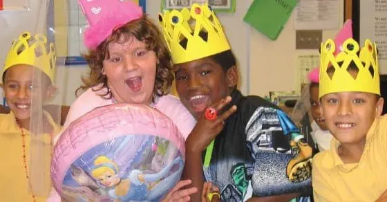 Four children wearing party hats and crowns smile for the camera.