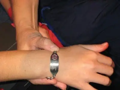A medical alert bracelet is on a person's wrist.
