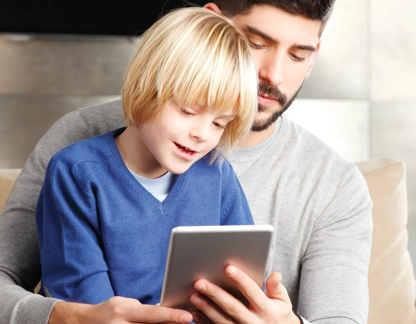 A father and son look at a tablet together.