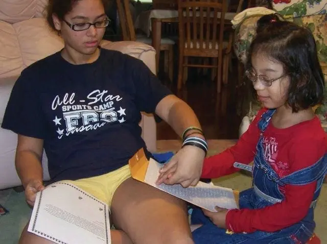 Two girls with glasses looking at papers.