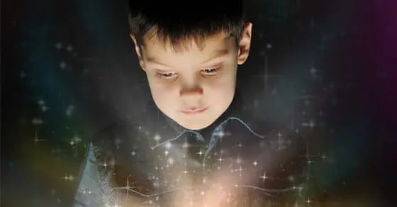 Young boy looking down at a glowing light surrounded by sparkles
