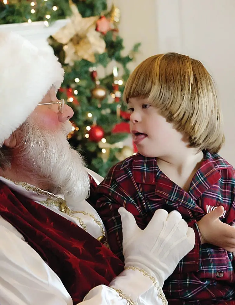 Landyn with Santa Claus in front of a Christmas tree.