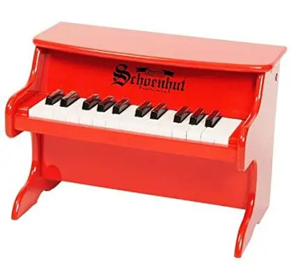 A red Schoenhut toy piano with white keys.