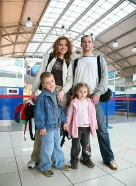 Family poses for a photo at an indoor travel terminal.