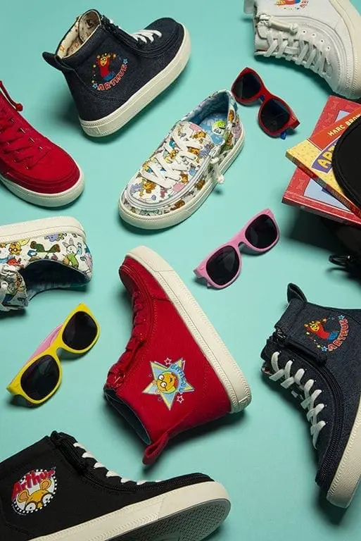 Assortment of children's footwear and sunglasses arranged on a blue background.