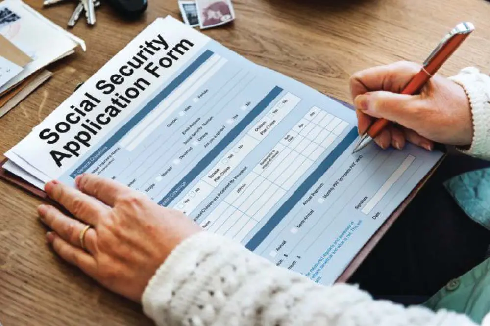 Social Security application form with a person filling it out.