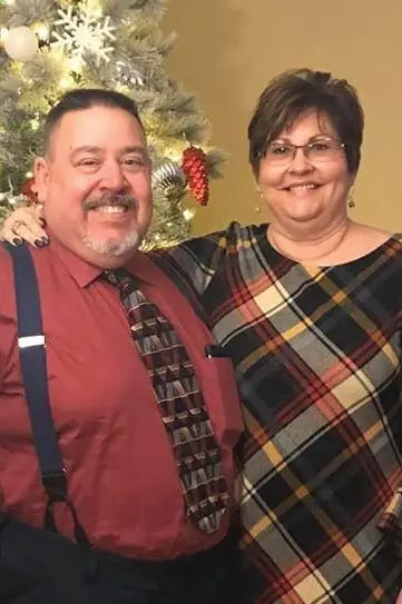 Joe and Lee Ann Mersol smiling in front of a Christmas tree.