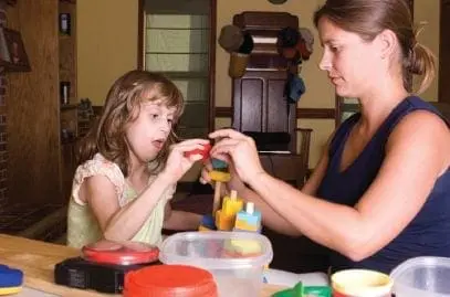 Woman and child playing with toy blocks at a table