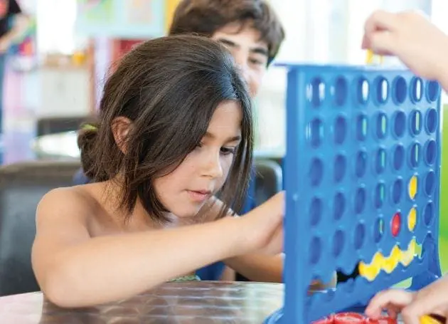 Children playing Connect Four at a table.