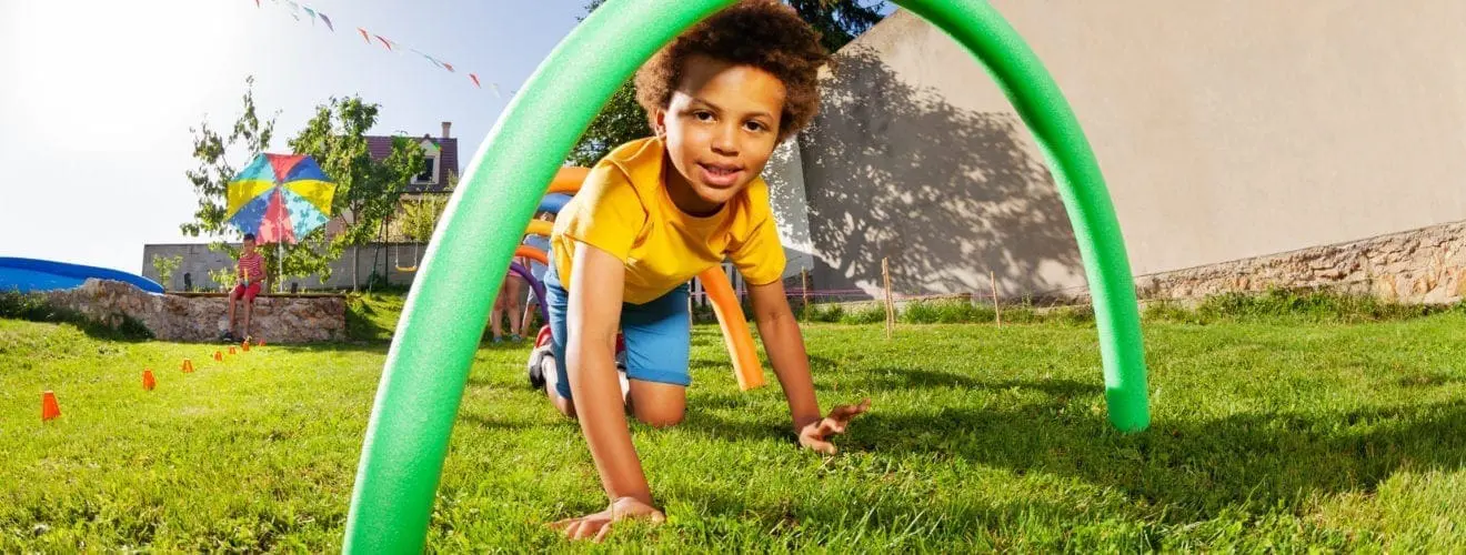 Kids crawl under course of barriers on his fours