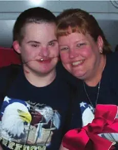 Seth and his mother smile together, with a red bow in the foreground.