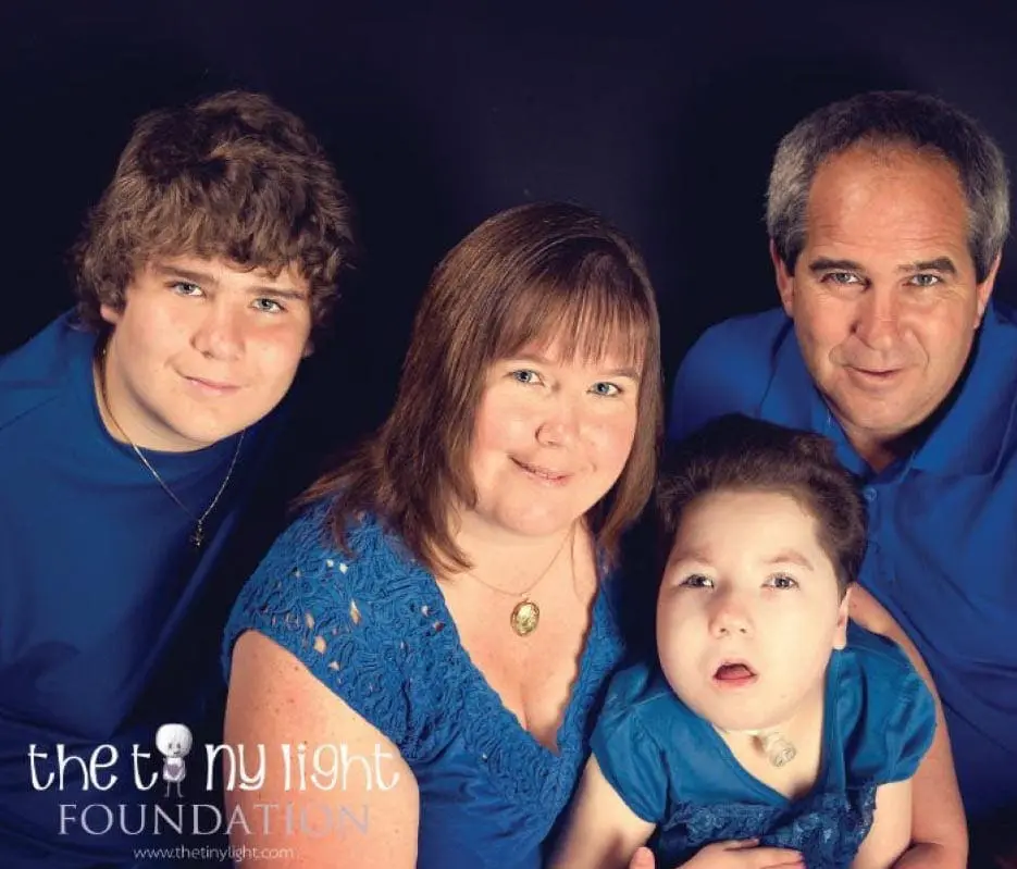 Emily and her family in blue shirts against a dark background.