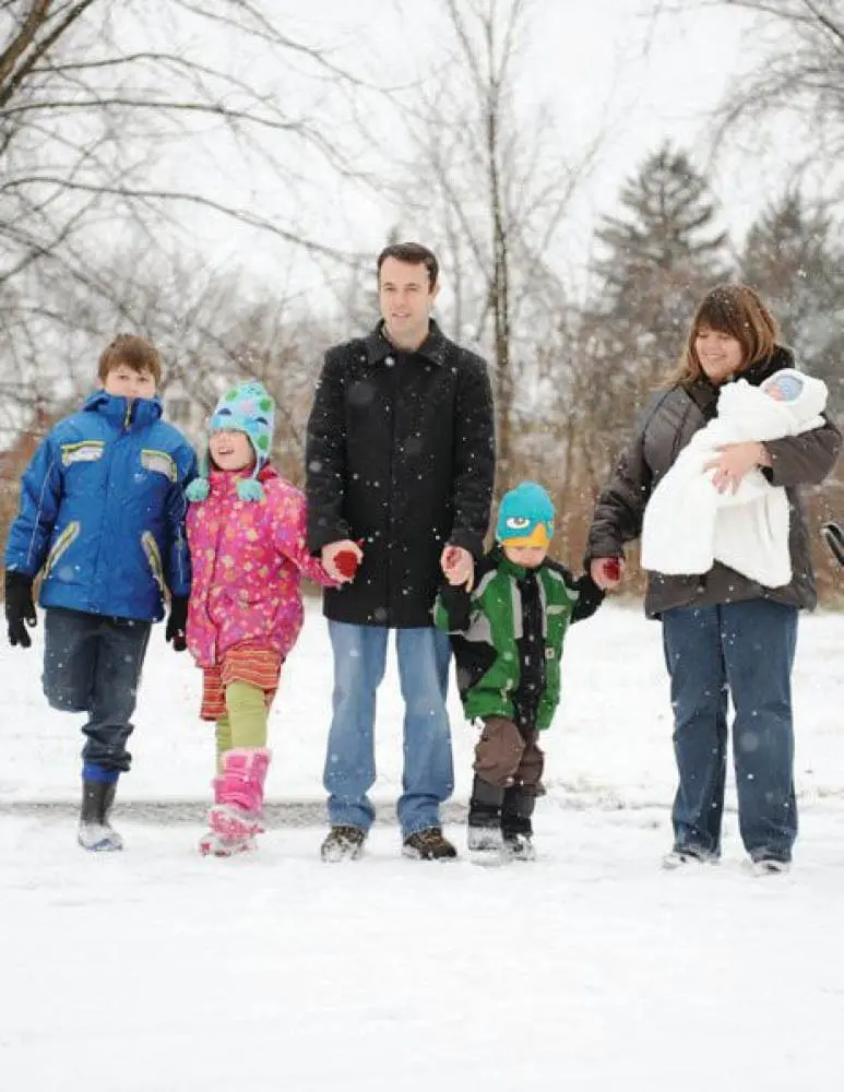 Family of five holding hands in the snow