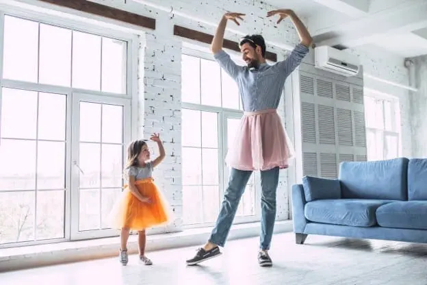 Woman and child dancing in a sunlit room.