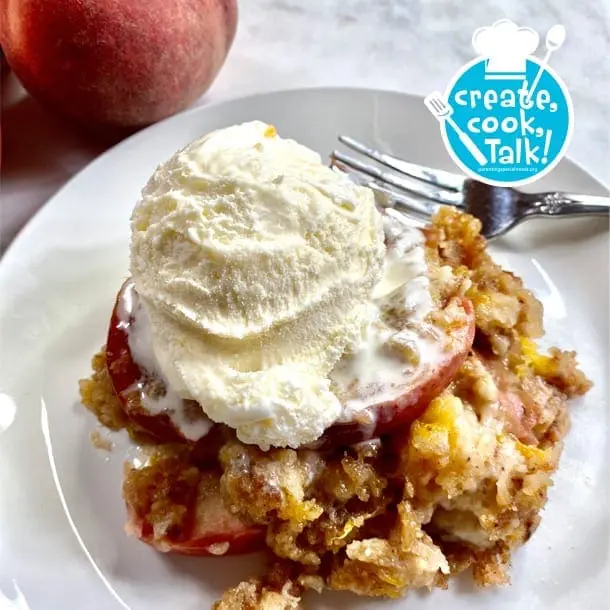 Peach dump cake topped with vanilla ice cream on a white plate.