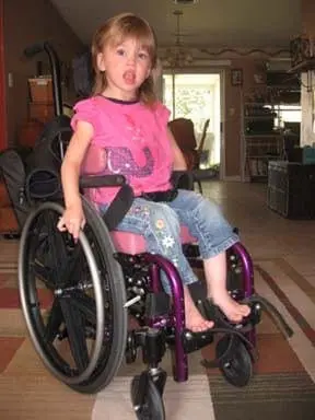 Young girl in a wheelchair in a home setting.