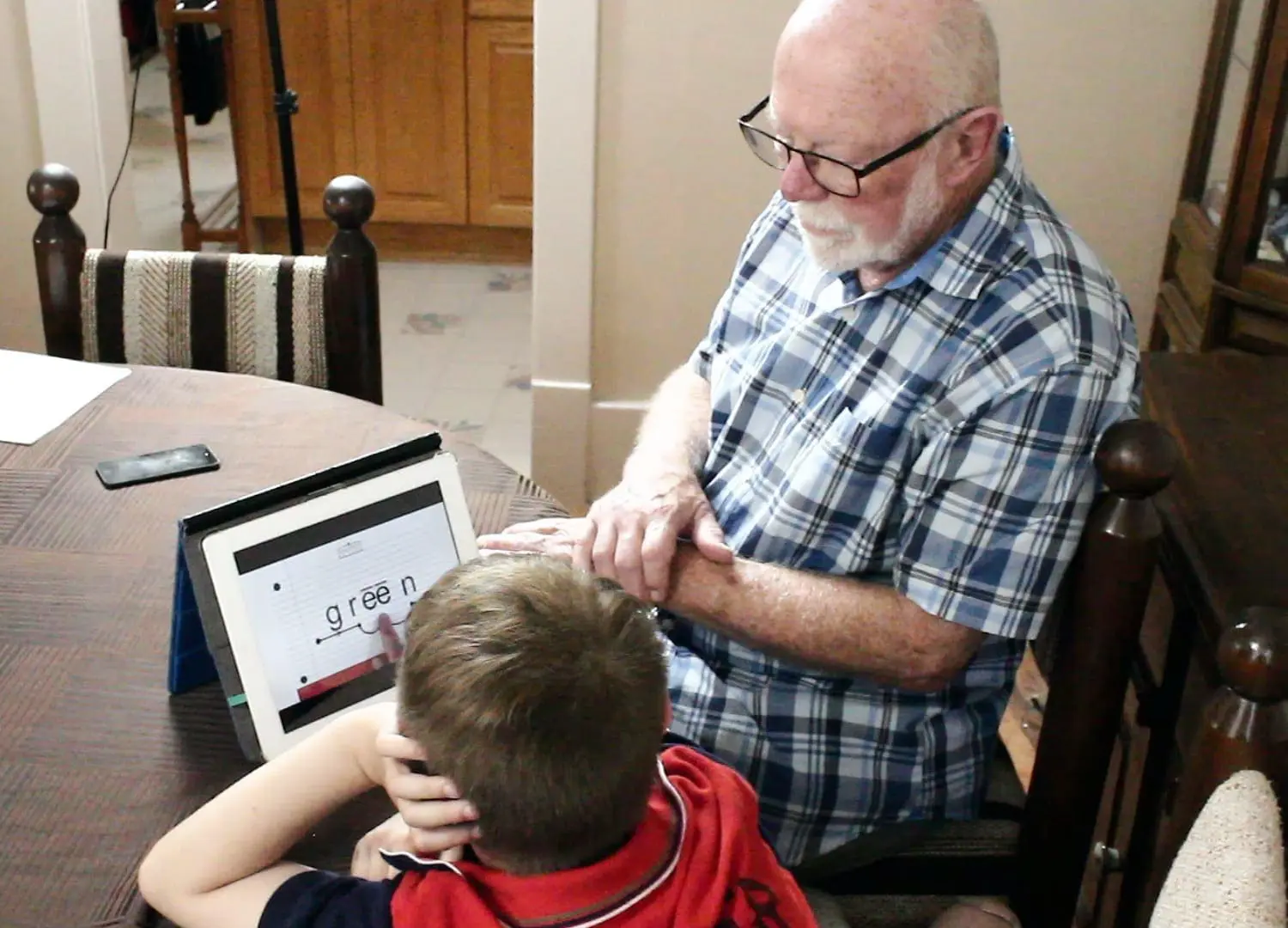 MM Michael with a student at a table looking at a tablet.