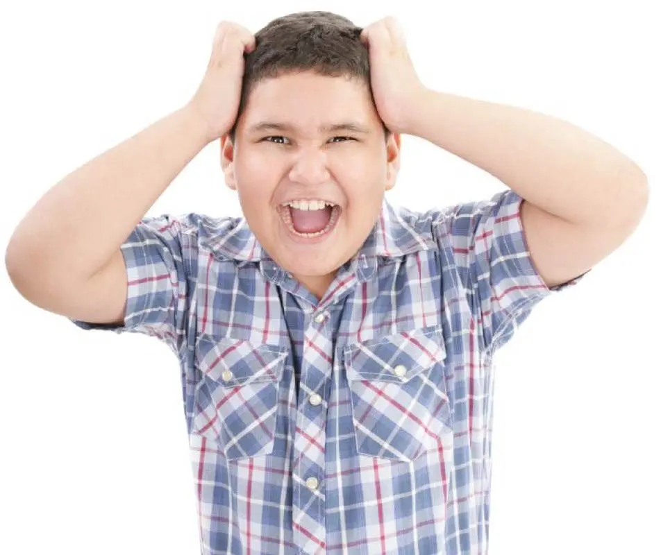 Boy with hands on head, mouth open in distress.