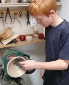 Austin Bruder sanding a wooden bowl on a lathe.