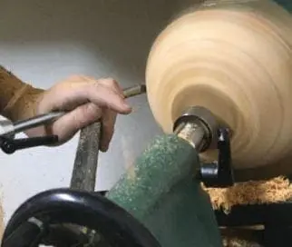 Austin Bruder working on a wood lathe with woodworking tools.