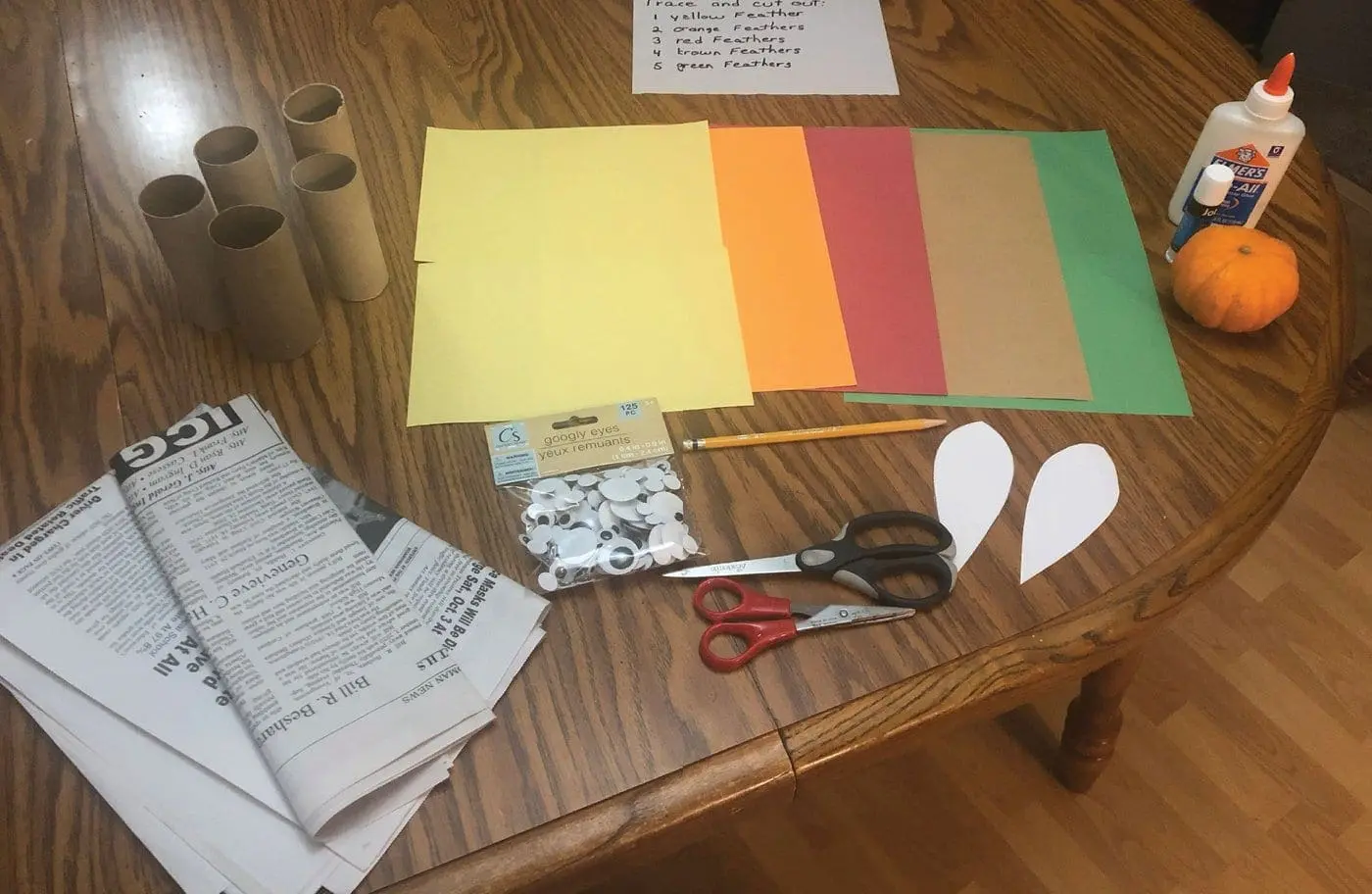 Craft supplies for turkey bowling including toilet paper tubes, construction paper, scissors, and googly eyes.
