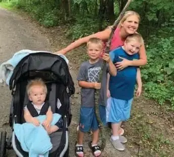 Kate Swenson with three children, one in a stroller, outdoors on a path.