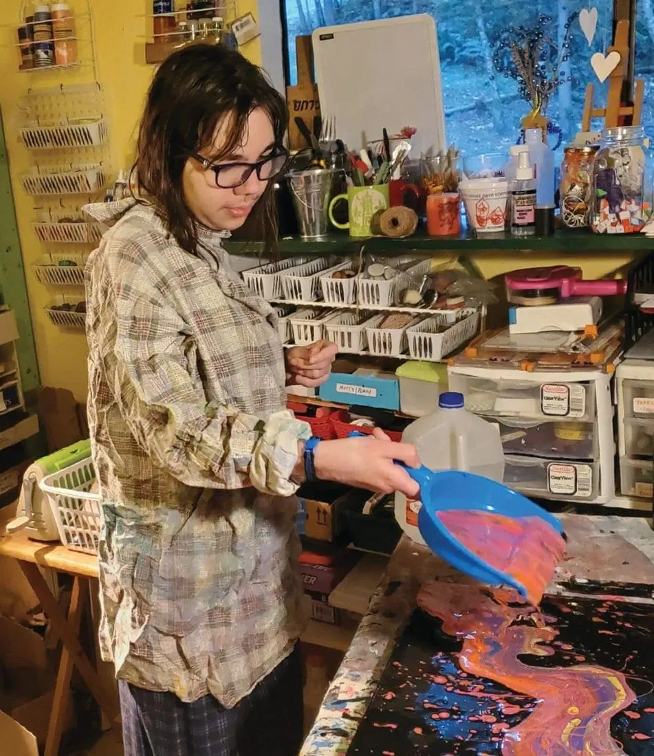 Kodie Smith pours paint onto a canvas in her art studio.