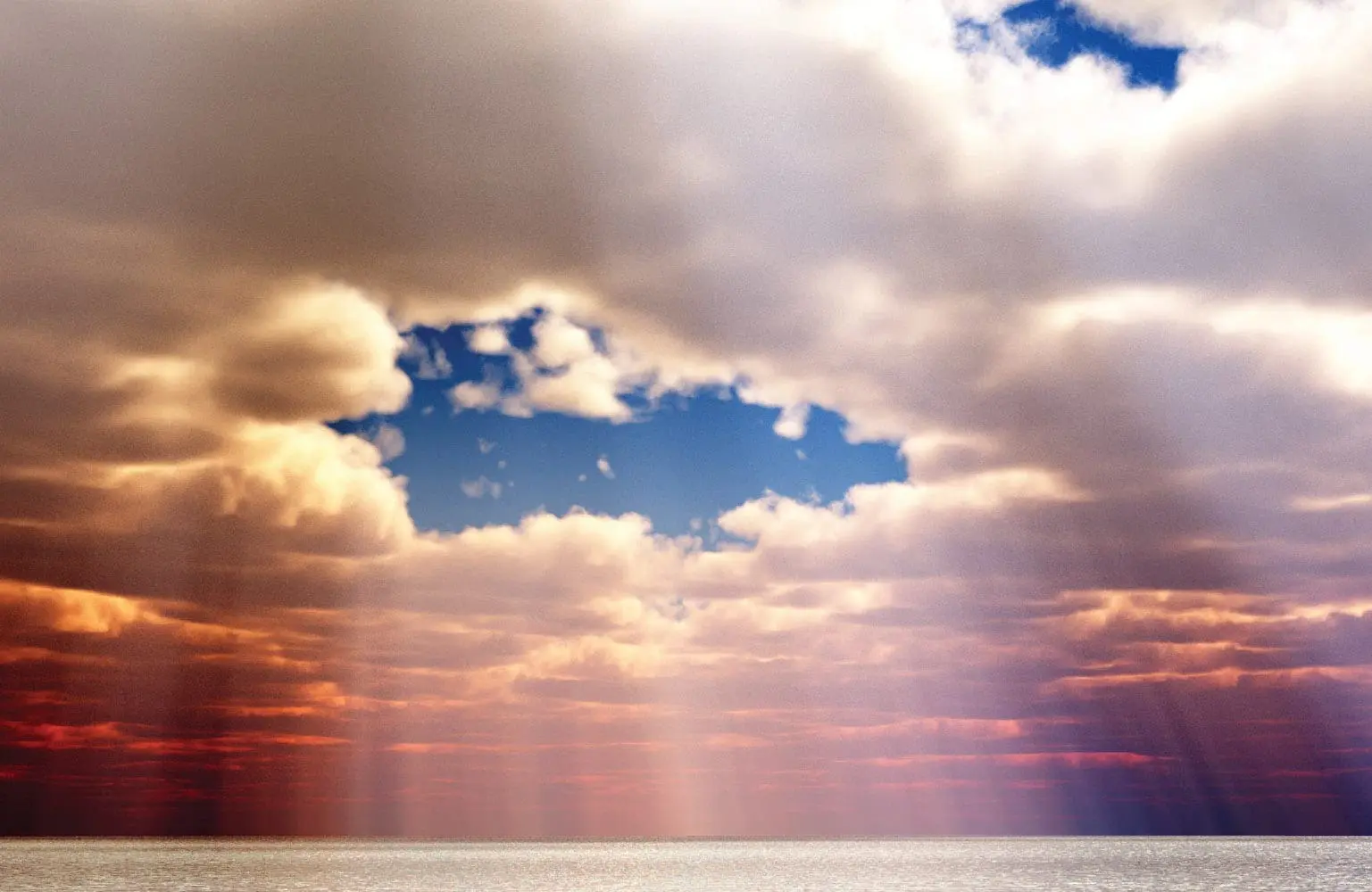 Sunlight streams through a gap in dramatic clouds over a calm body of water.