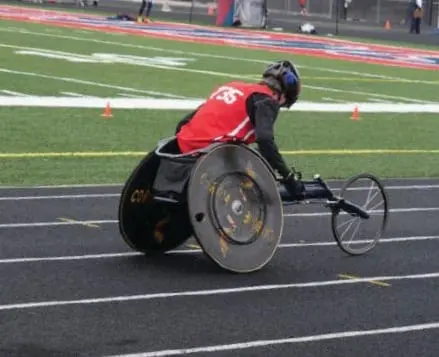 Cody in a racing wheelchair on a track
