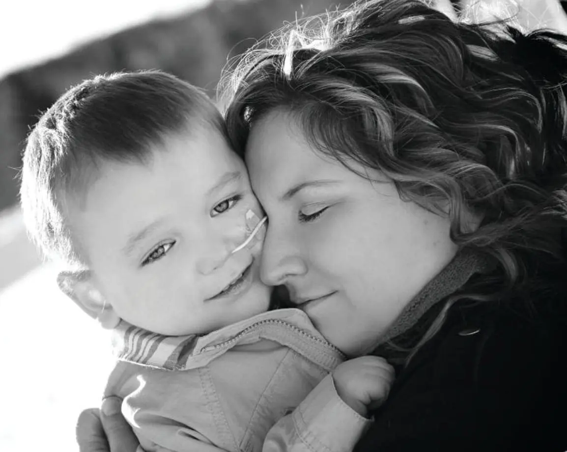 Lukas smiles as his mother holds him close.