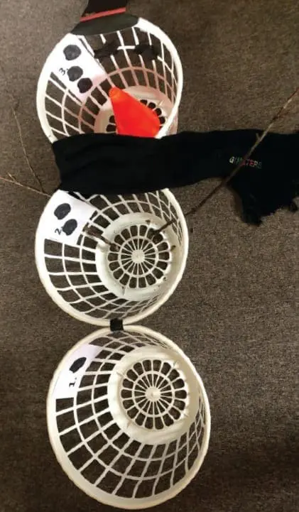 Snowman made from three white laundry baskets, with a black scarf and orange nose.