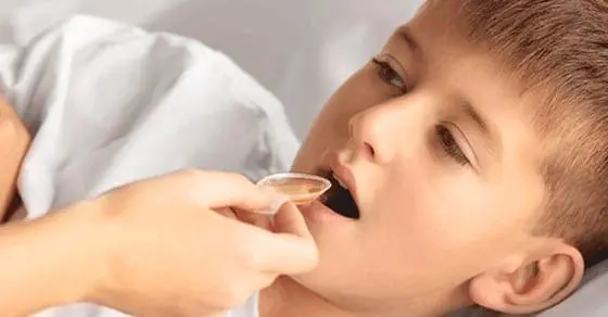 Child being given liquid medicine in a dosing cup