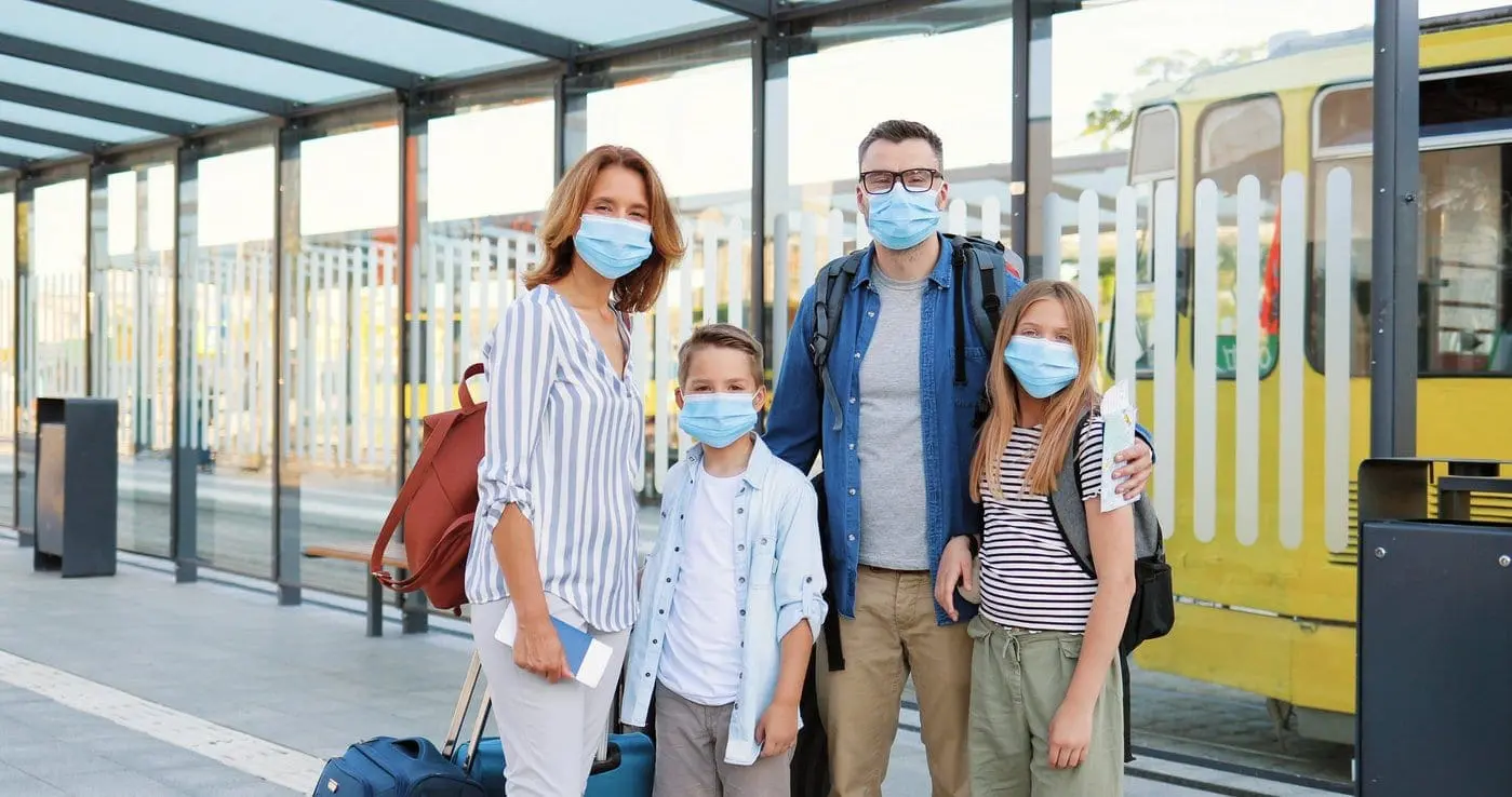 Family in masks with suitcases at a train station
