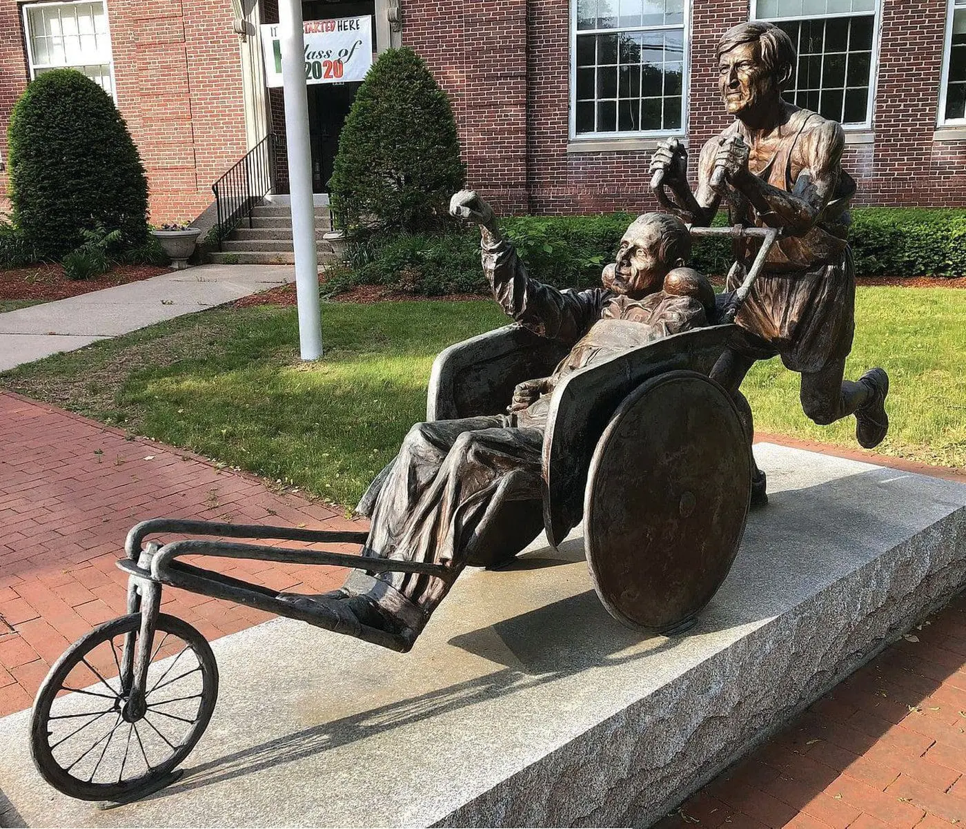 Bronze statue of Dick Hoyt pushing his son Rick in a wheelchair.
