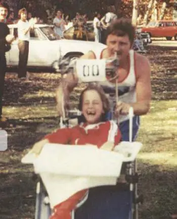 Dick Hoyt pushing his son Rick in a wheelchair with a joyful expression.