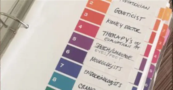Binder with color-coded tabs listing various medical specialists.