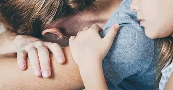 A child hugs an adult from behind.